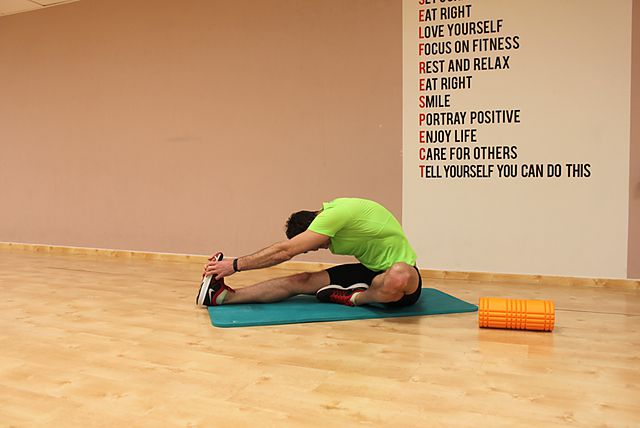 Фото упражнения Растяжка мышц задней поверхности бедра сидя на полу